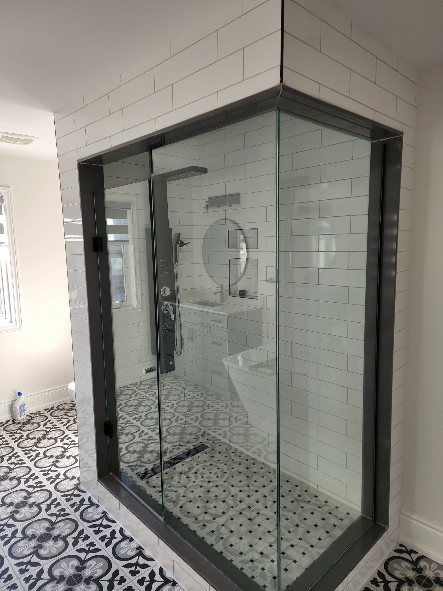 Glass shower enclosure with patterned floor tile