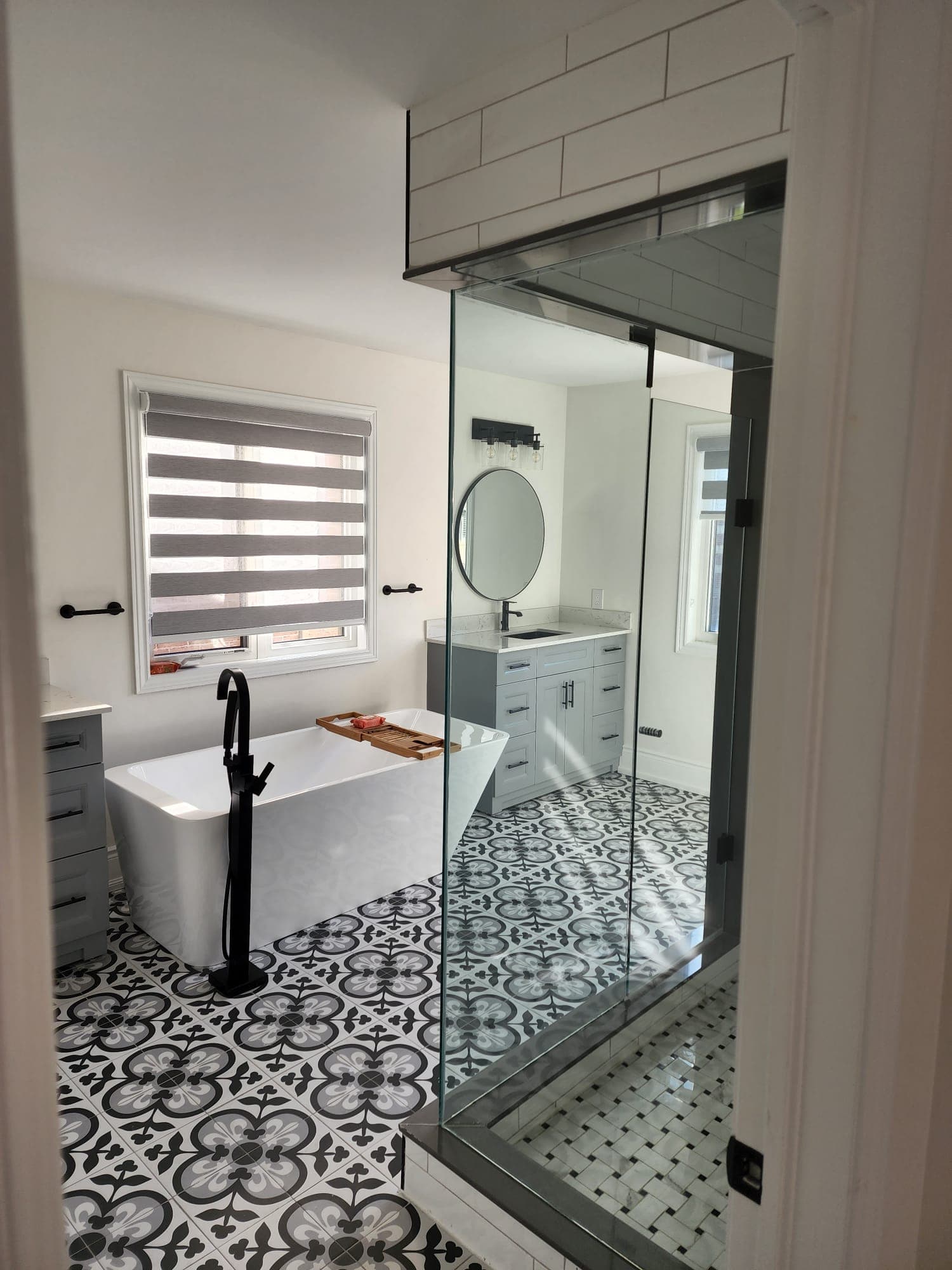 Freestanding tub with patterned tile floor and glass shower