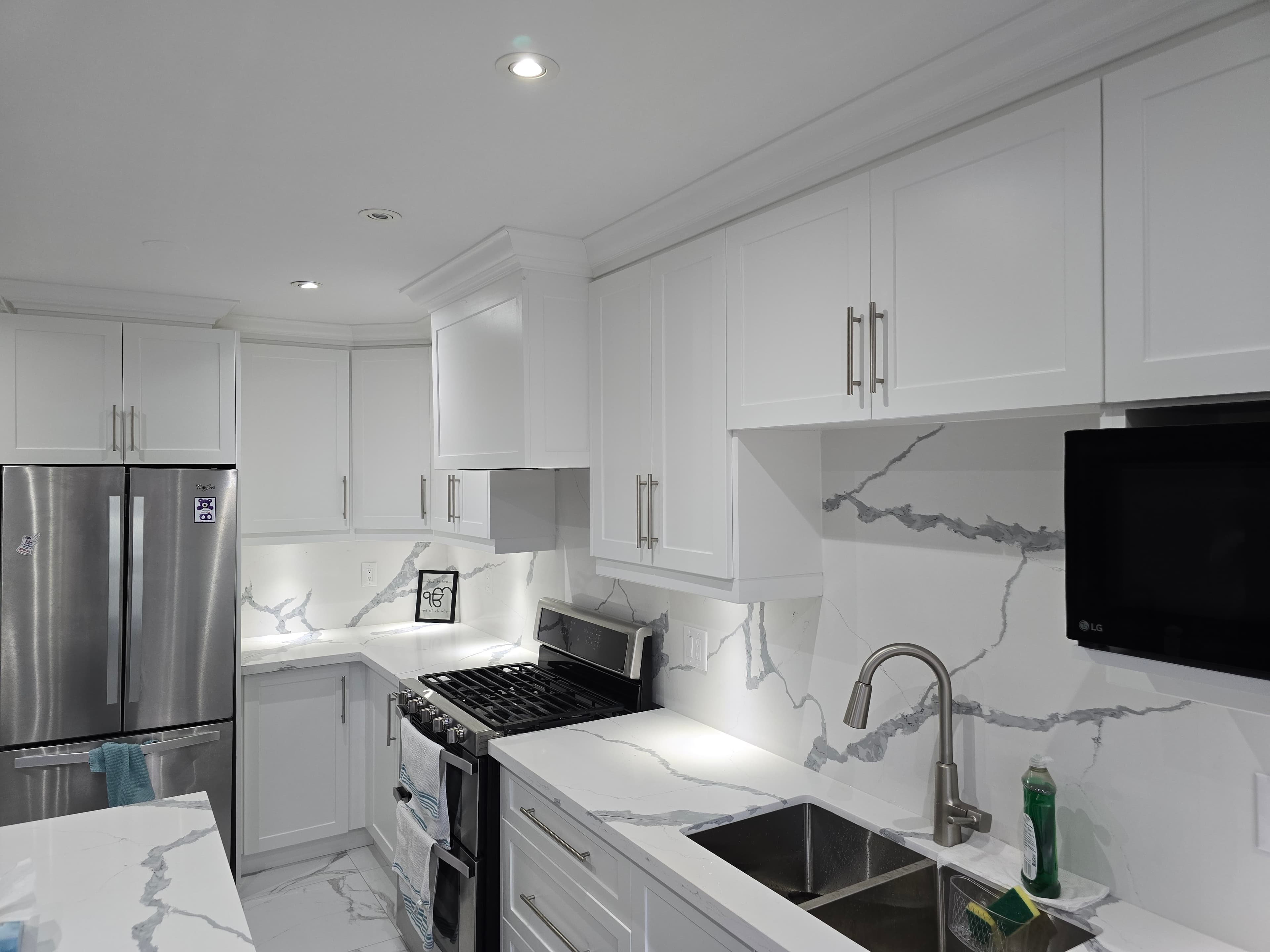 White kitchen with quartz countertops and marble backsplash